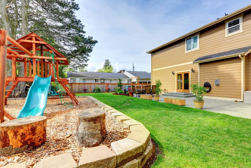 backyard patio with a synthetic grass lawn and play area