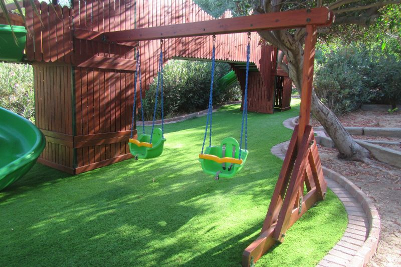 playground with swings and artificial grass