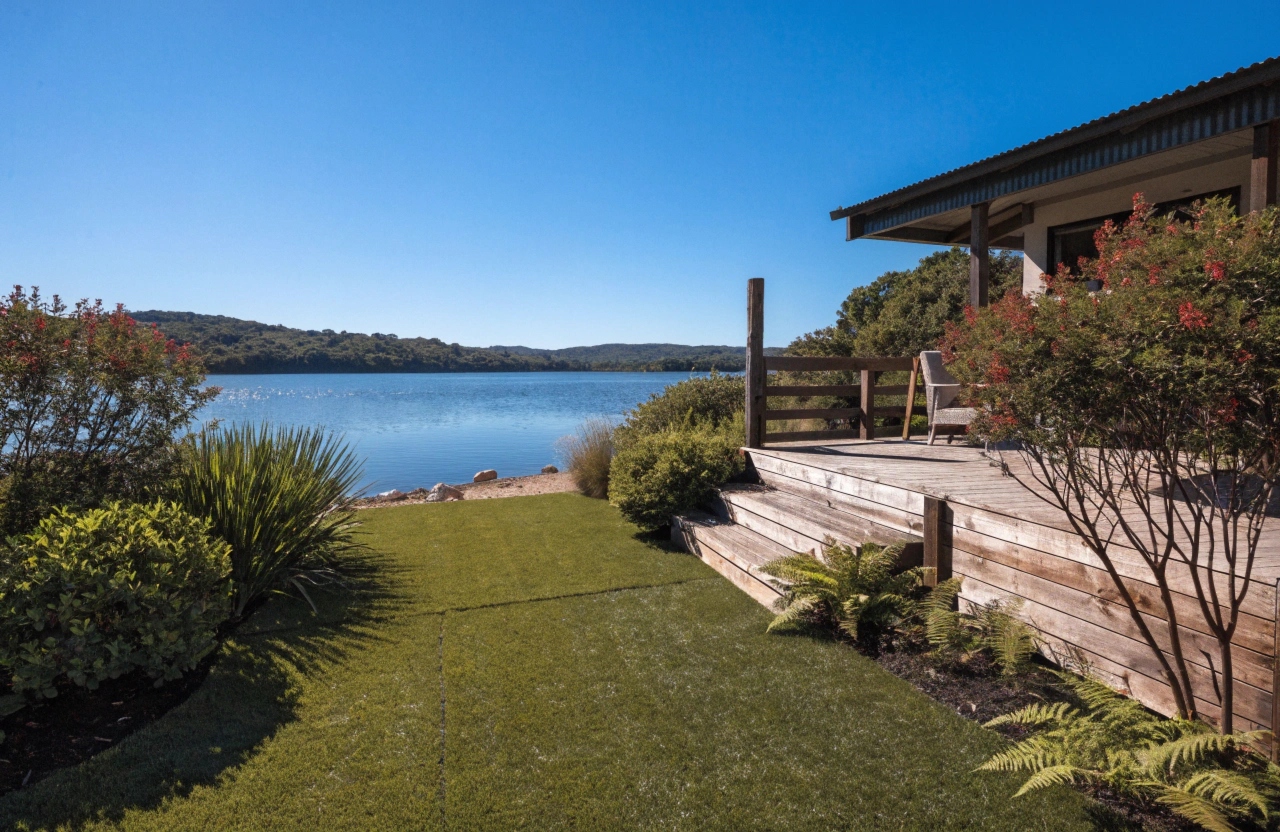 Synthetic grass installation in a lakeside Lake Macquarie backyard with timber deck and garden borders